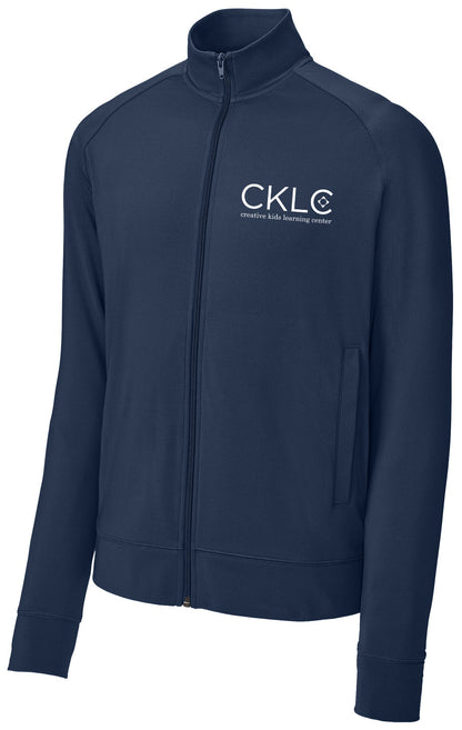 The Creative Kids Learning Center CKLC Sport-Tek Sport-Wick Stretch Full-Zip Cadet Jacket (ST857) is navy blue with raglan sleeves, a high collar, front pockets, and features the CKLC logo and text in white on the left chest.