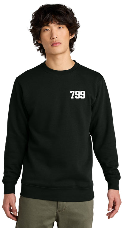 A young person with wavy hair wears the black LKOT Crewneck Sweatshirt — Adult, featuring a white 799 on the left chest, against a plain white background.